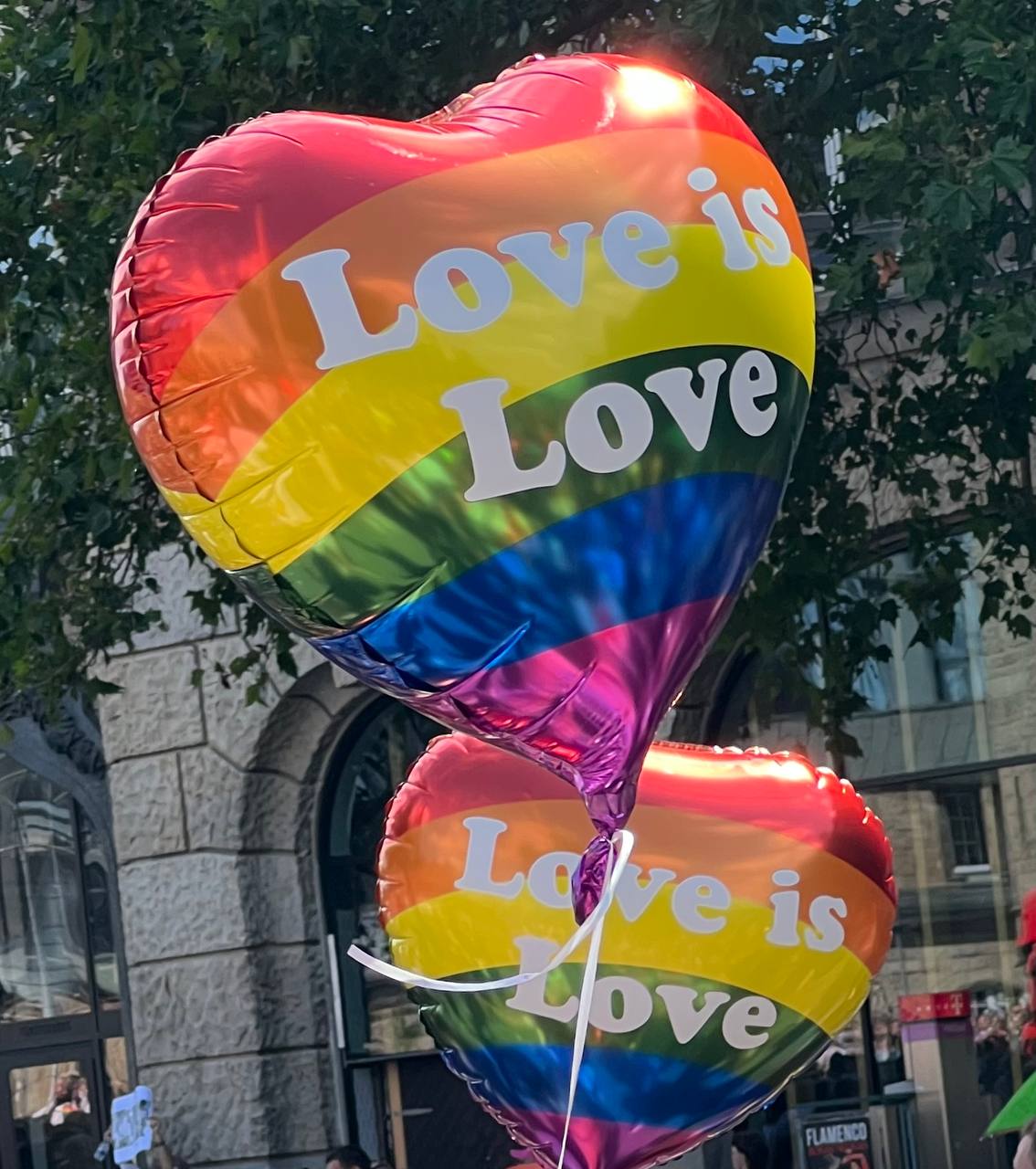 Herzluftballons in Regenbogenfarben mit der Aufschrift „Love is Love“